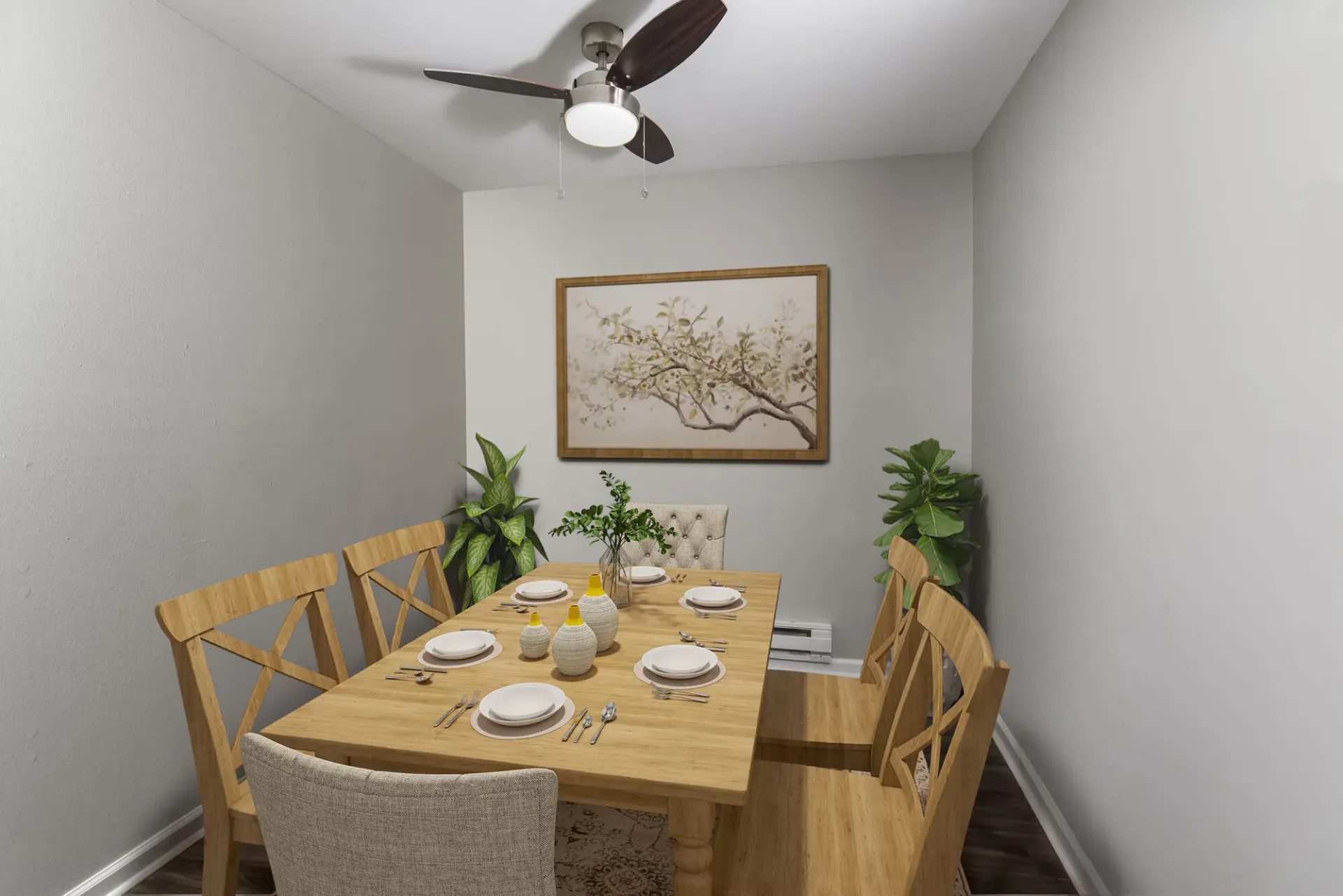 Dining area in a compact apartment with a wooden table, chairs, ceiling fan, and plants at The Addison, offers townhomes for rent in North Wales near Delaware Valley University.