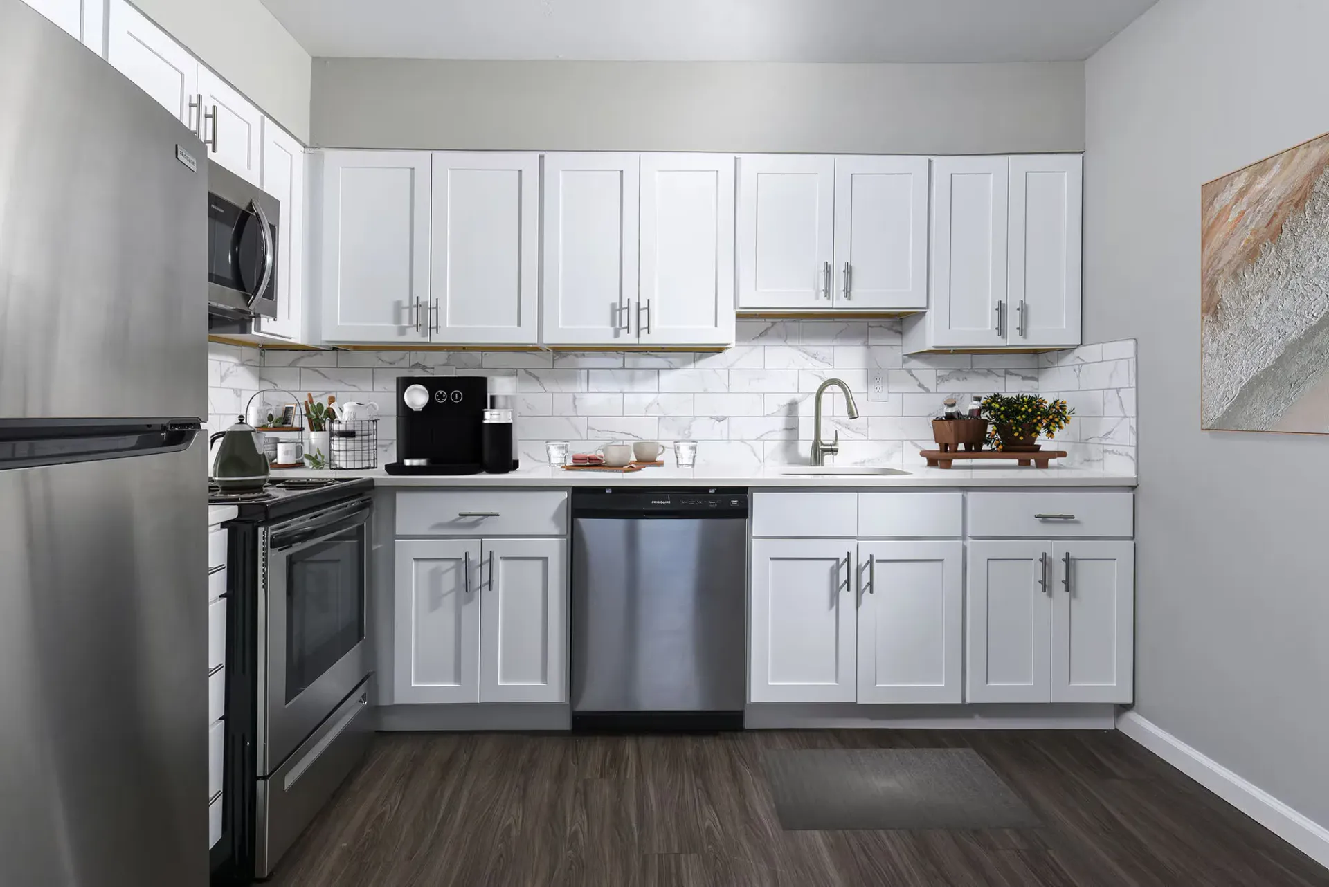 Modern kitchen with white cabinets, stainless steel appliances, and marble backsplash at The Addison, offers apartments for rent in North Wales near Gwynedd Mercy University.