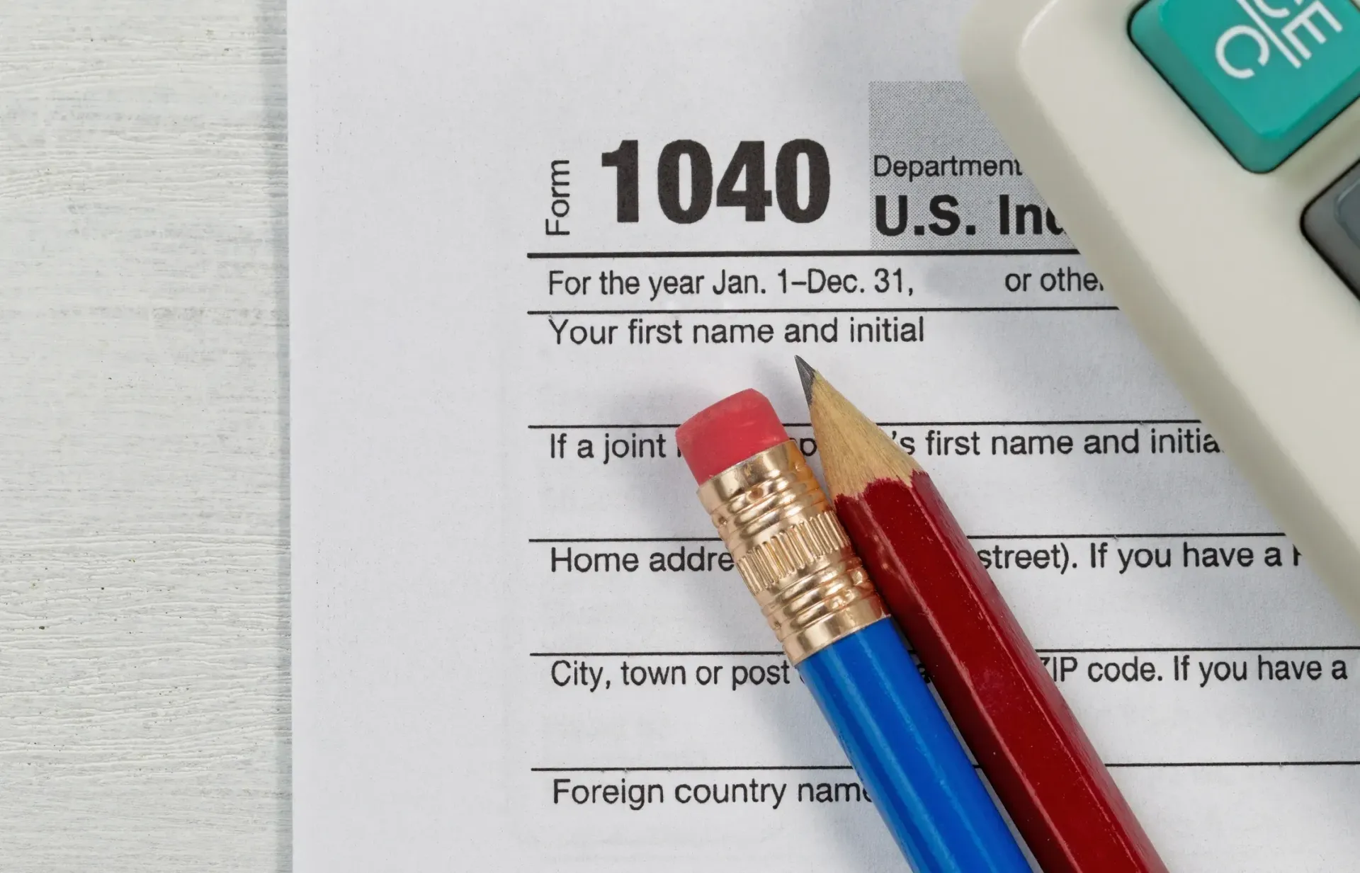 Tax form 1040 with pencils and a calculator, on a white surface.