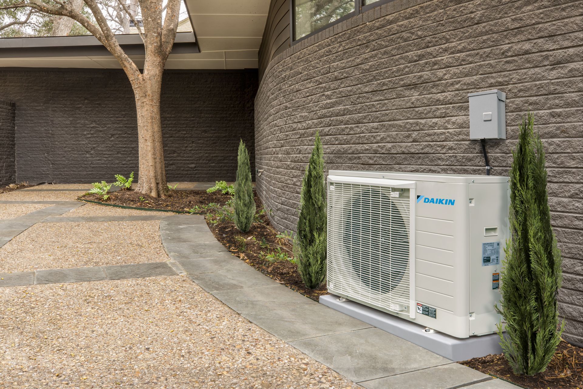A large Daikin Fit air conditioner is sitting on the side of a brick building.