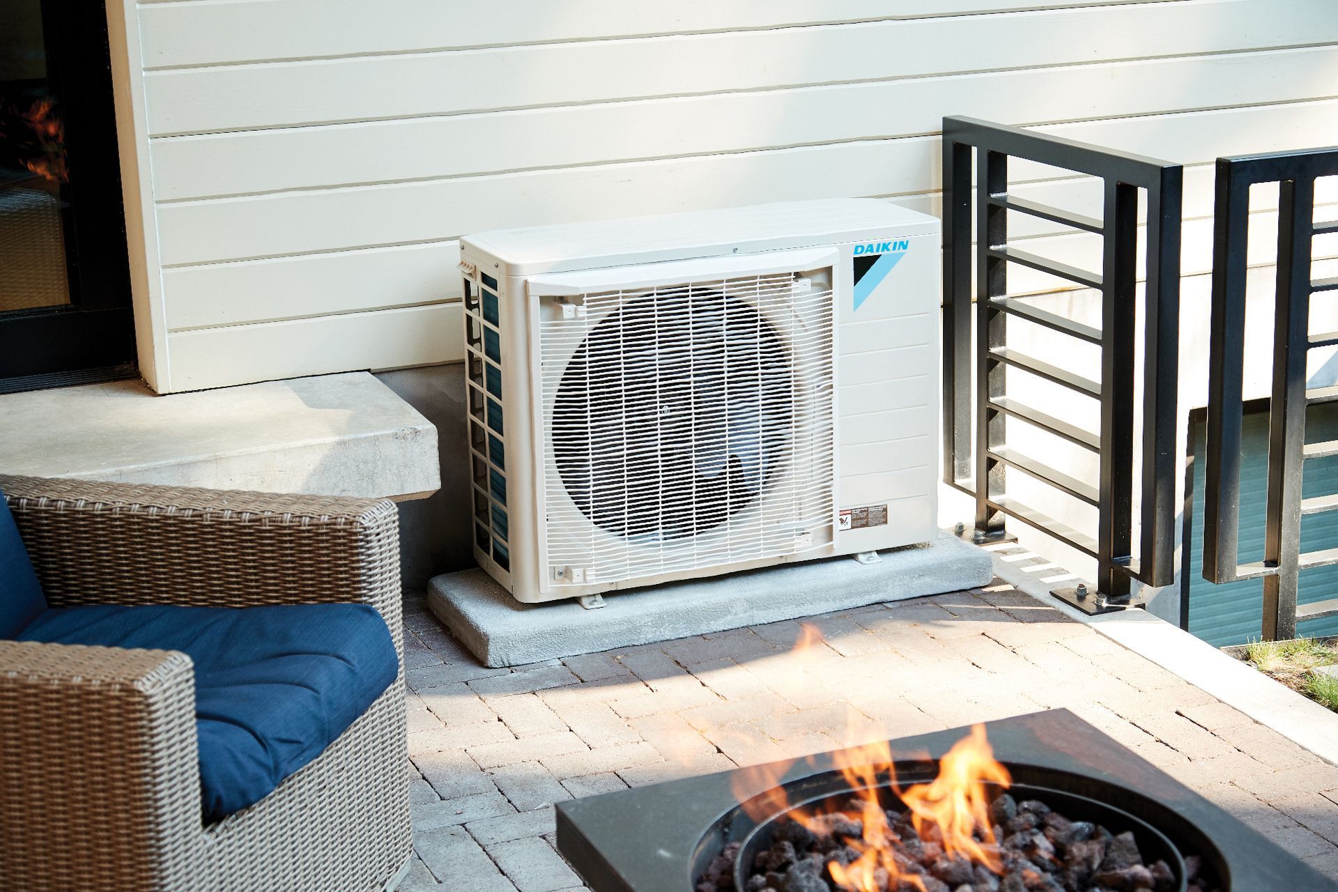 A Daikin Fit air conditioner is sitting on a patio next to a fire pit.