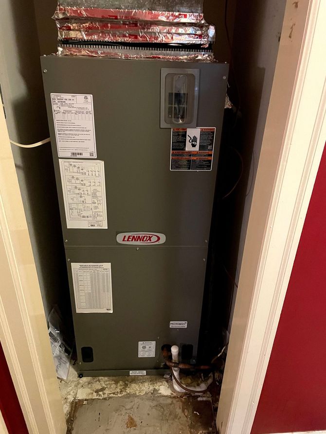 Lennox HVAC unit in a utility closet with ductwork, set against red and beige walls.