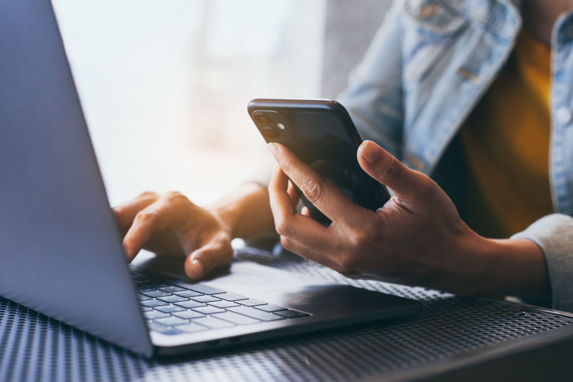 A person is using a laptop and a cell phone at the same time.