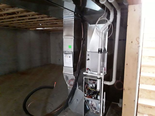 Exposed HVAC or electrical equipment with ducts and wires installed in a basement crawl space.