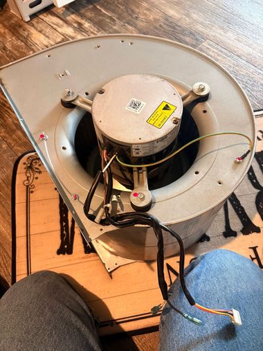 Close-up of a detached ceiling fan motor with exposed wires on the floor.