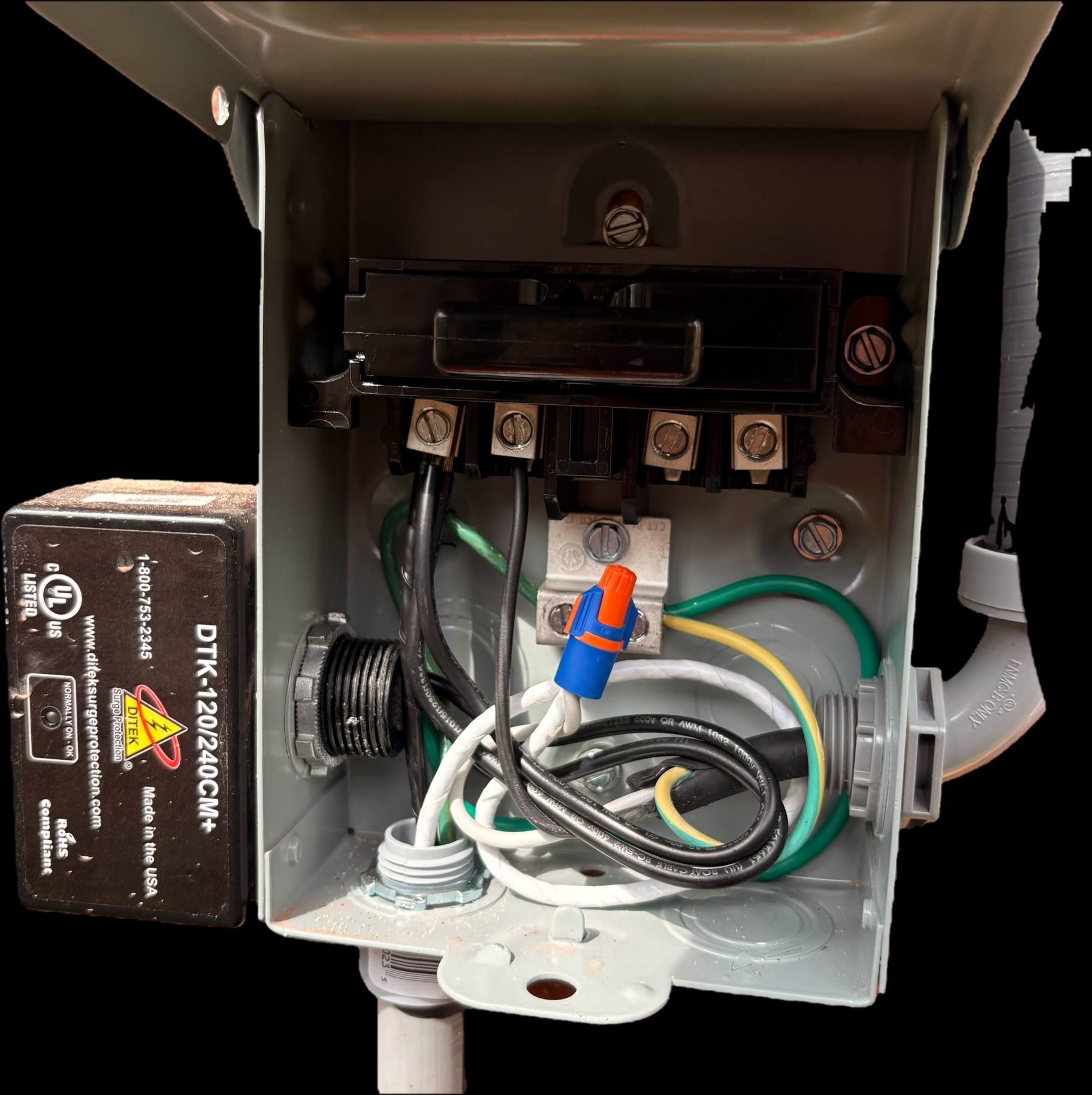 Open electrical panel with wiring, terminal blocks, and a black battery pack on the left.