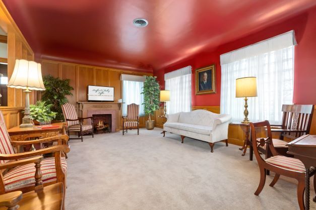 A living room with a couch , chairs , lamps and a fireplace.