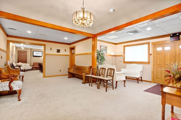 A living room with a couch , chairs , and a chandelier.