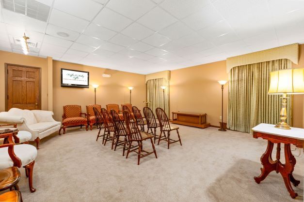 A room with a couch , chairs , a table and a television.