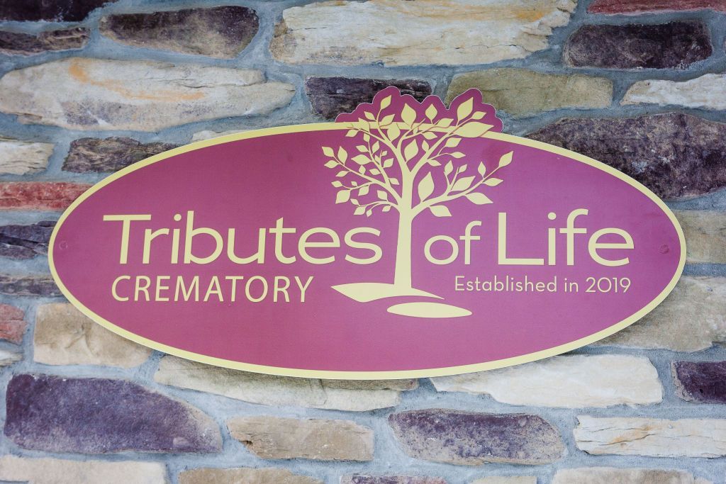 A sign on a stone wall that says tributes of life crematory