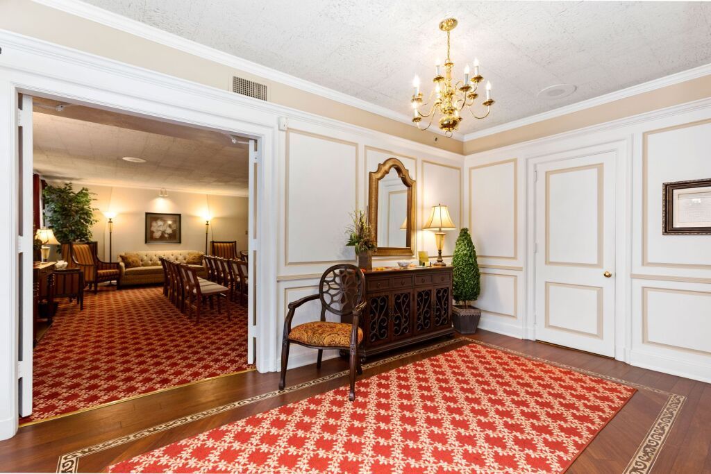 A living room with a red rug and a chandelier