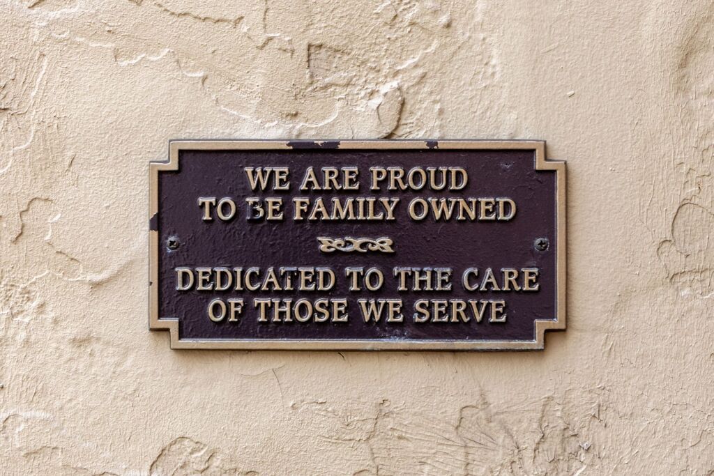 A sign on a wall that says we are proud to be family owned dedicated to the care of those we serve