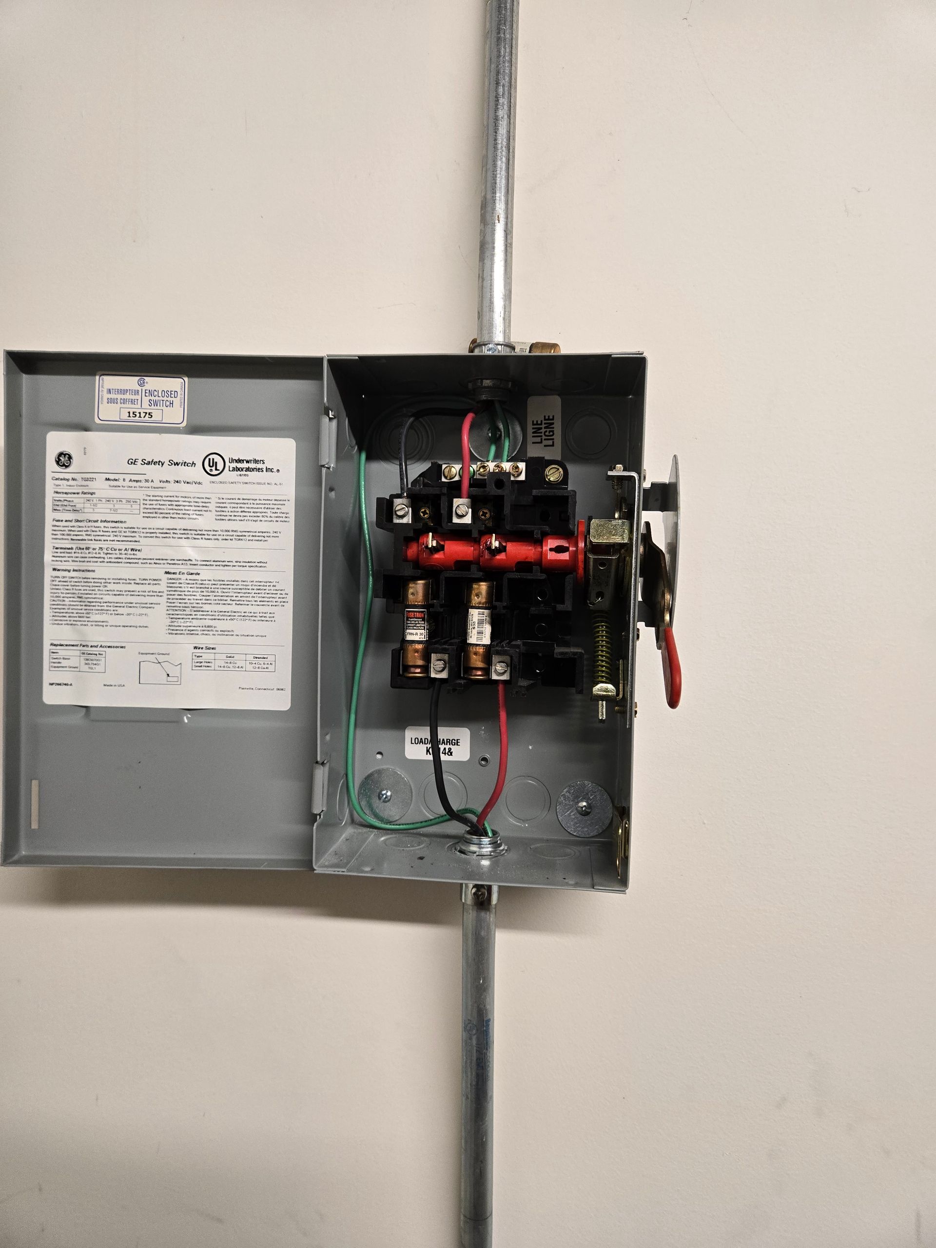 Open electrical junction box on a white wall with conduit. Wires and switches are visible.