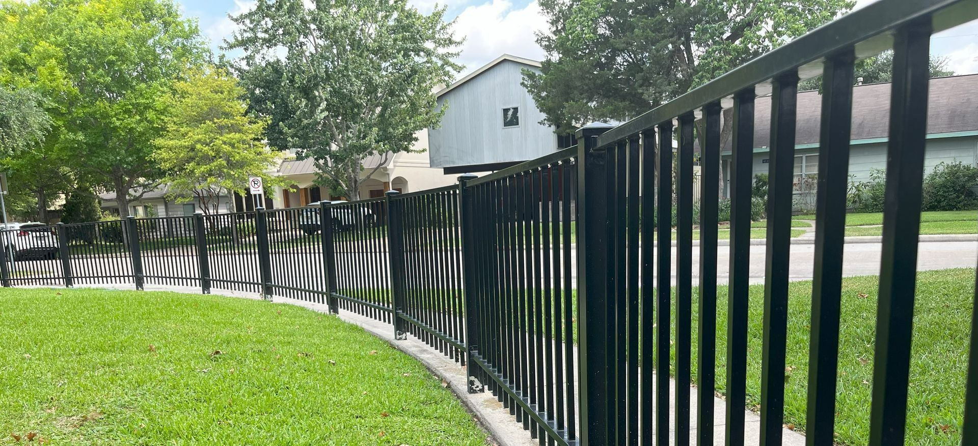 A curved short wrought iron fence surrounding a lawn