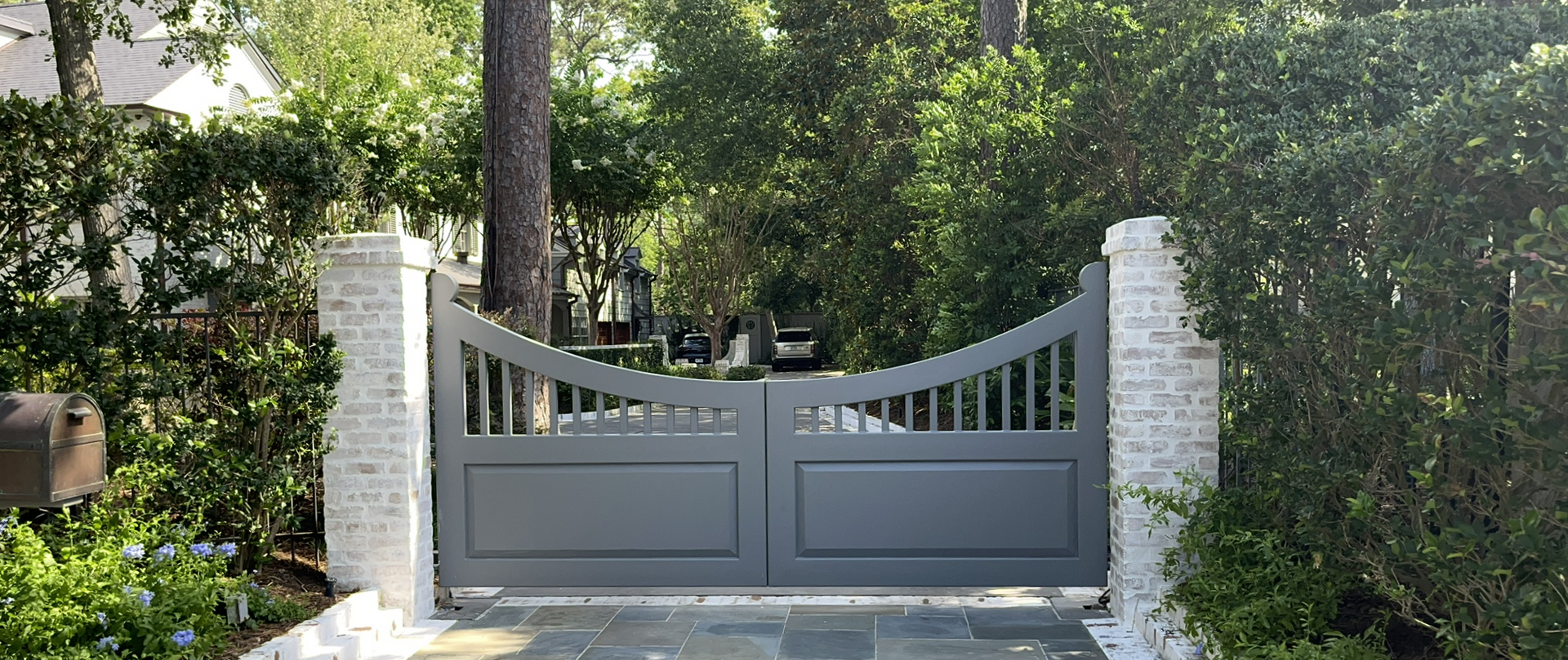 A beautiful grey metal and stone gate for a driveway.