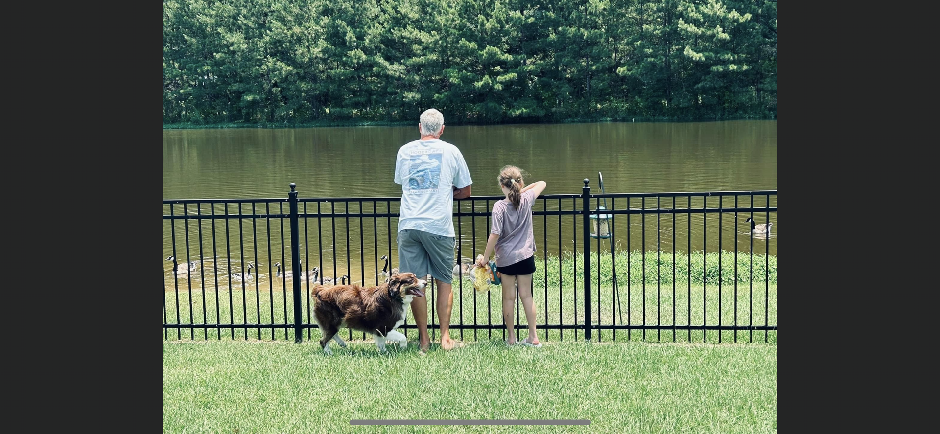 A family enjoying a wrought iron fence that surrounds their farm pond.
