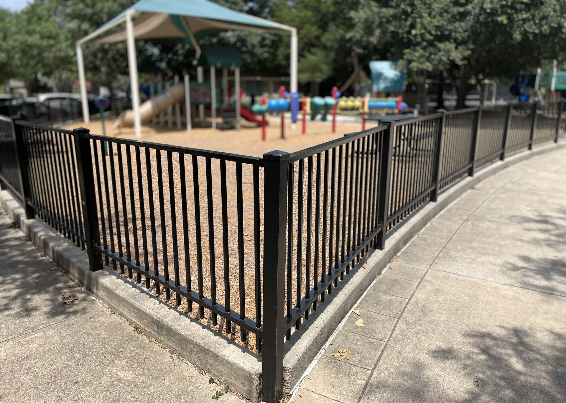 A wrought iron fence protecting a playground at a city park