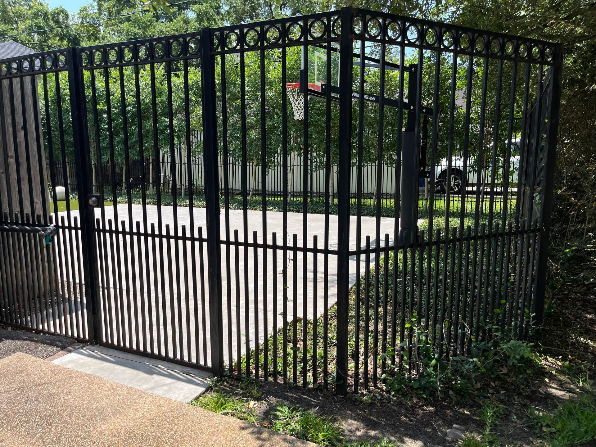 A tall wrought iron fence surrounding a home basketball court