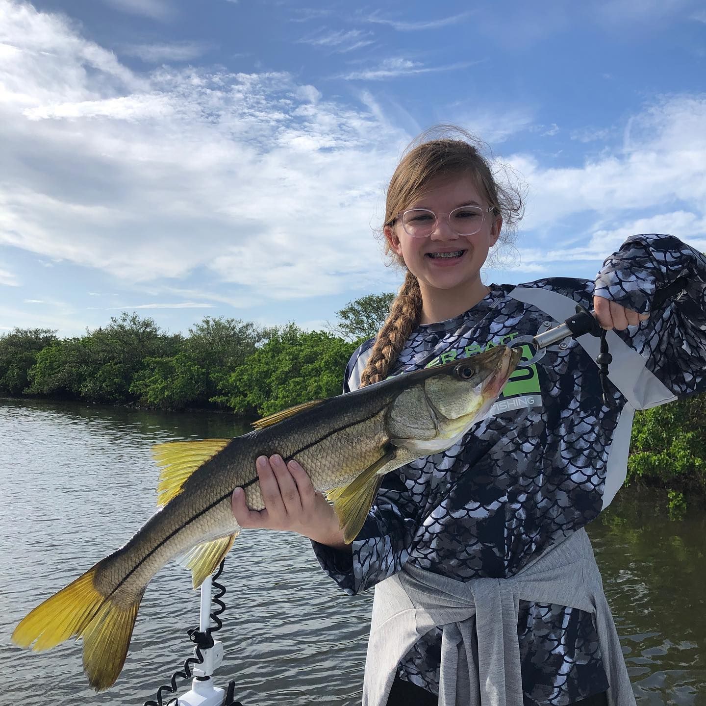 Girl on a boat holding a snook fish; sunny day on the water.