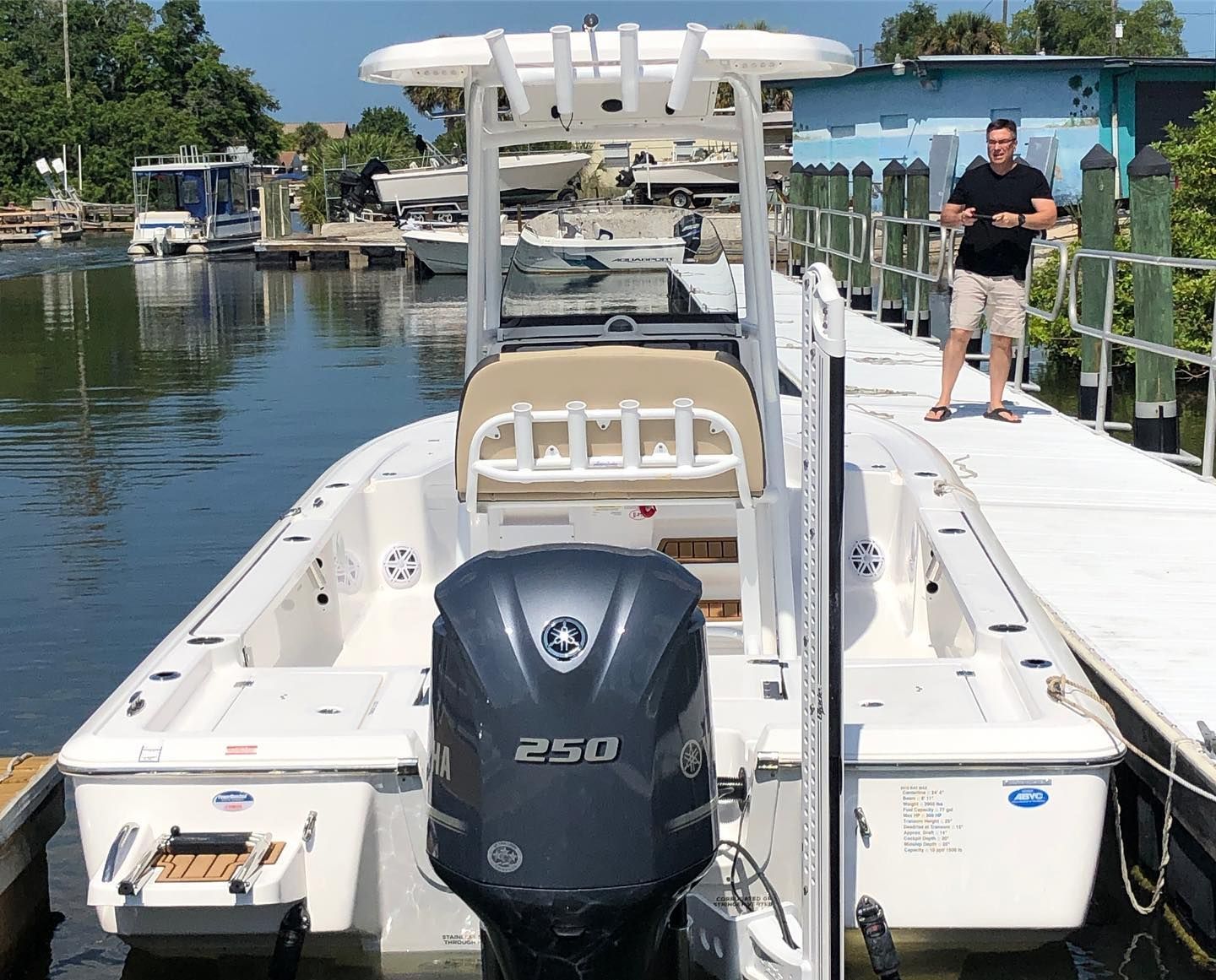 A white fishing boat docked near a man on a pier; the boat has a 250 HP engine.