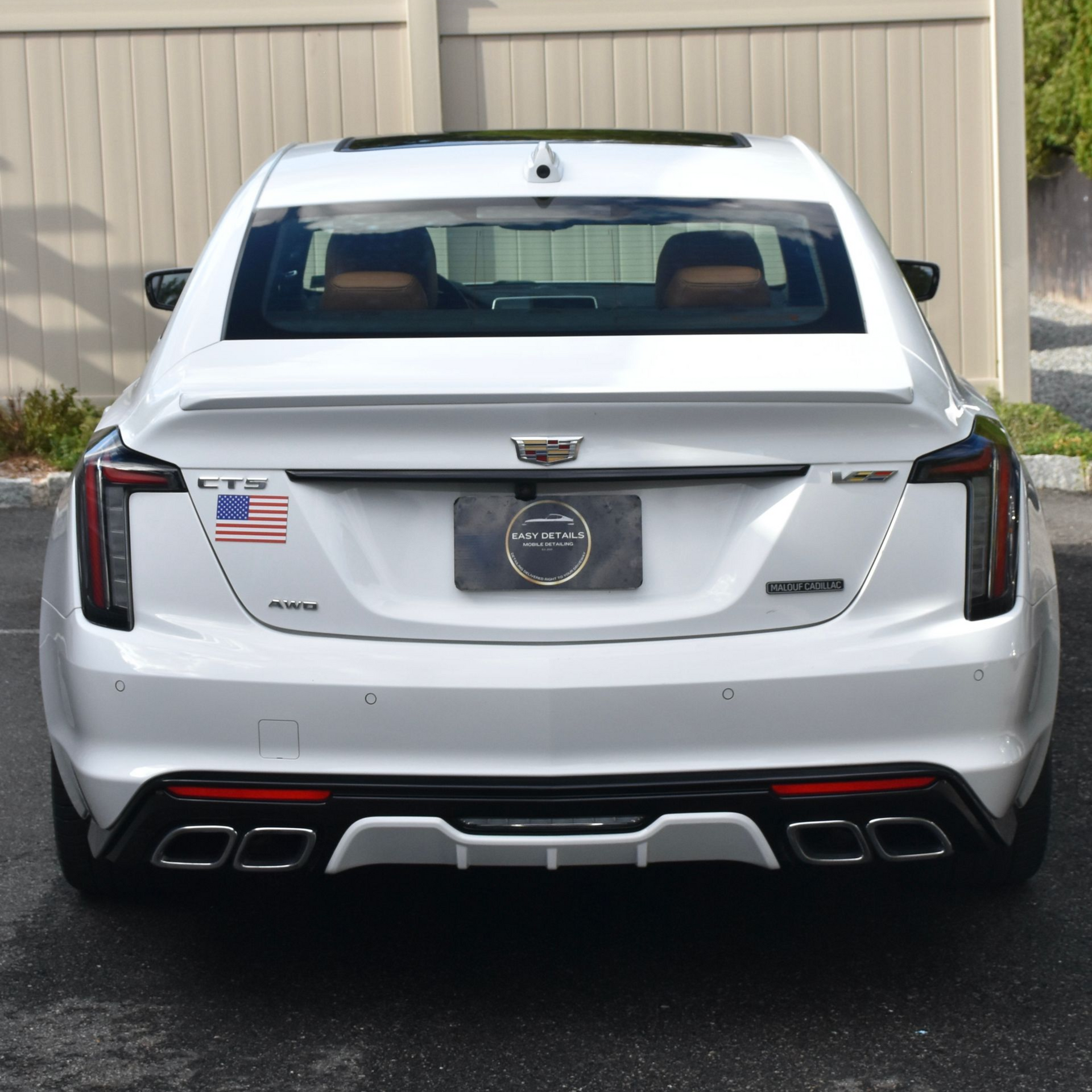 White Cadillac sedan with black accents, parked outdoors, rear view.