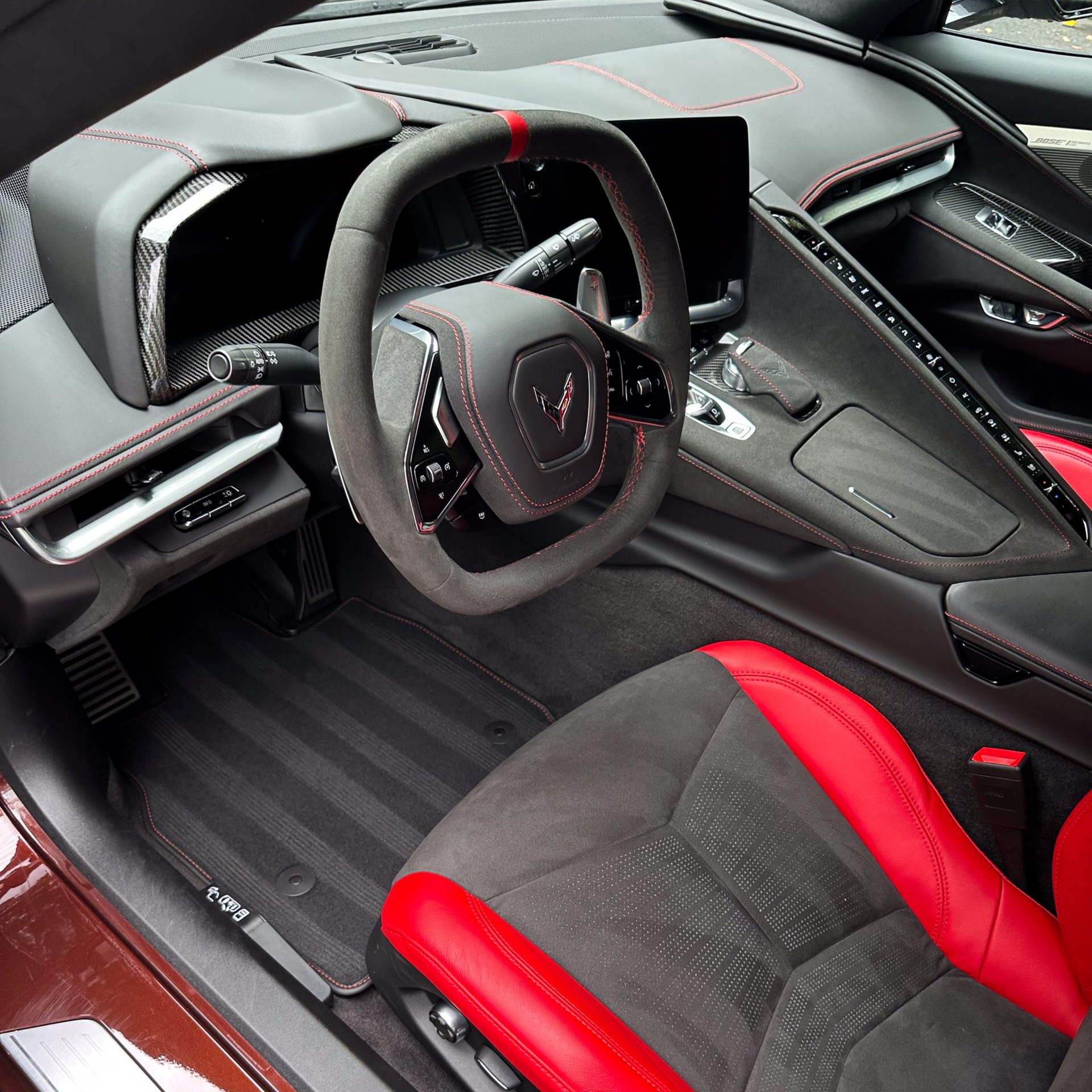 Interior view of a sports car, showcasing red and black seats and a steering wheel.