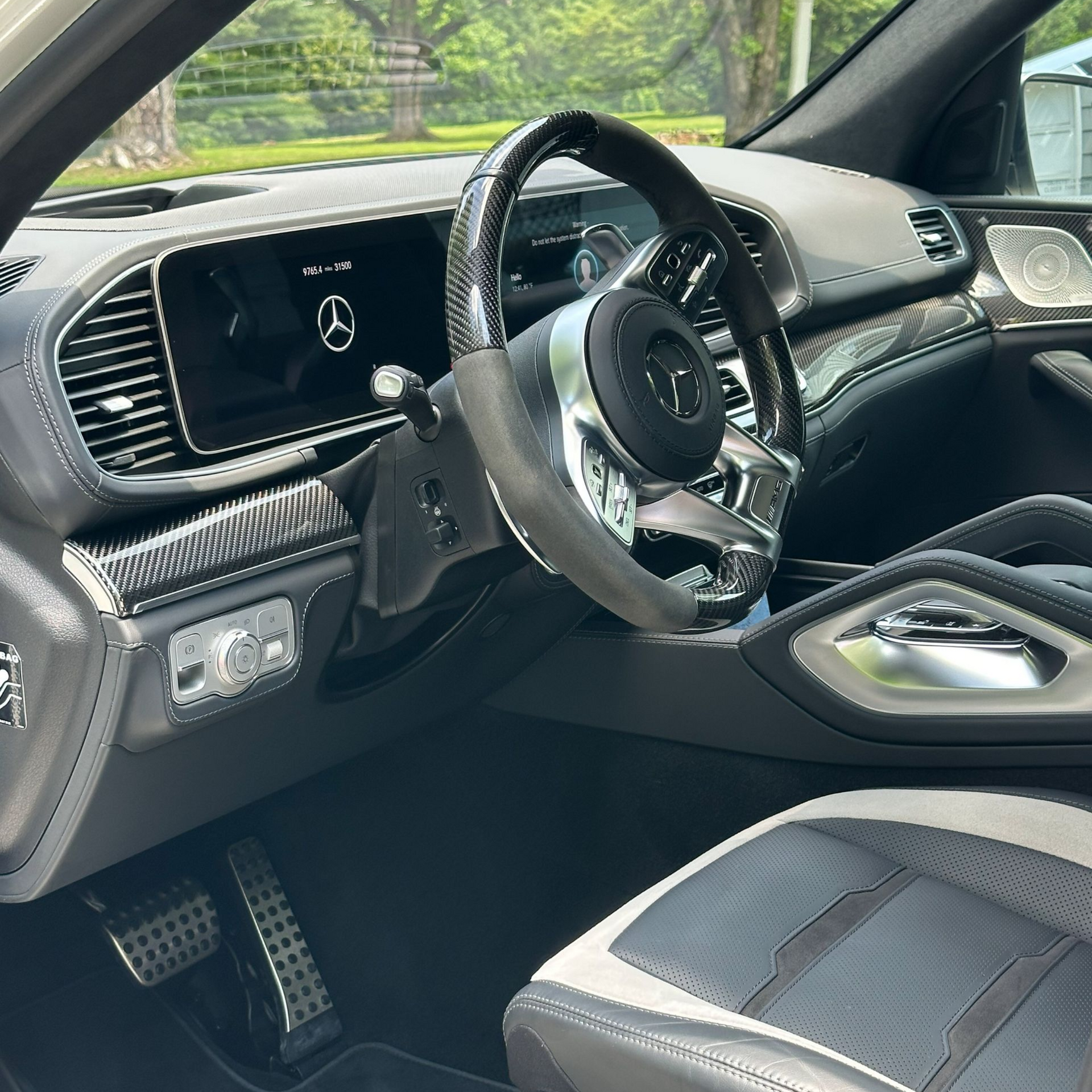 Mercedes-Benz SUV interior with black and silver accents. Steering wheel, dashboard, and seat visible.
