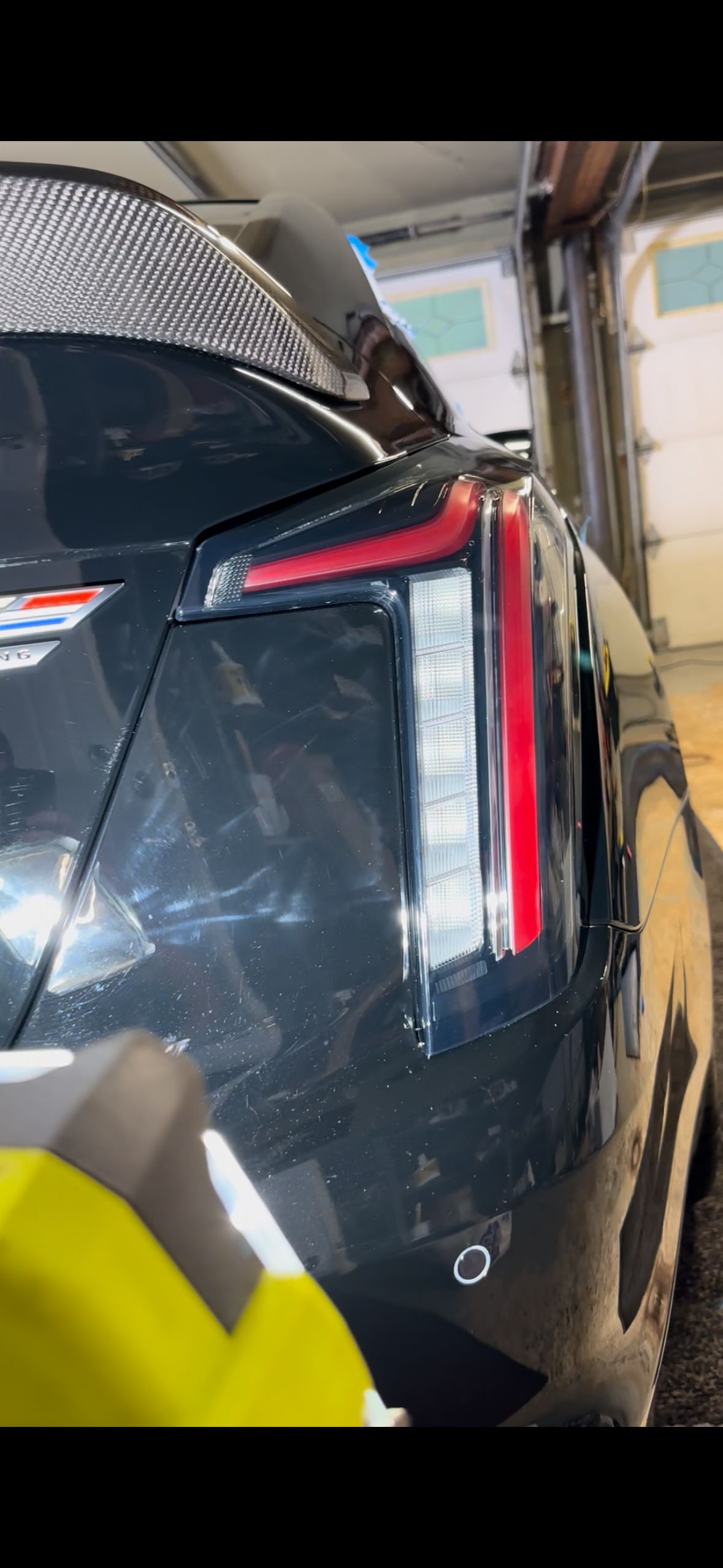 Black Cadillac rear with distinctive taillight design in a garage.