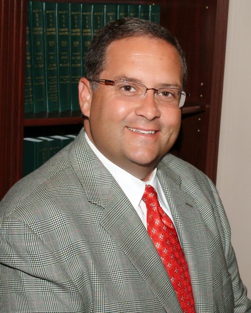 A man in a suit and tie is smiling for the camera