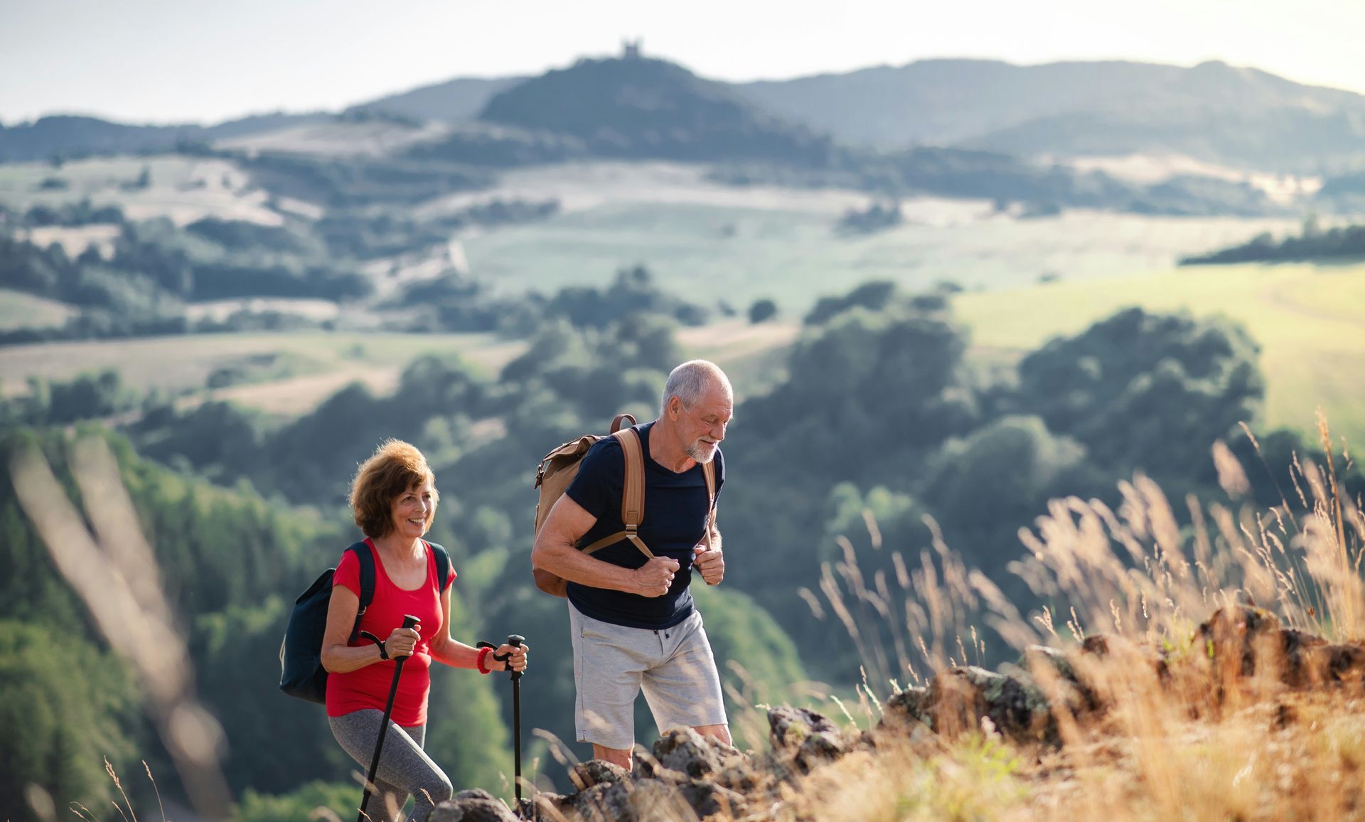 A man and a woman are hiking up a hill.