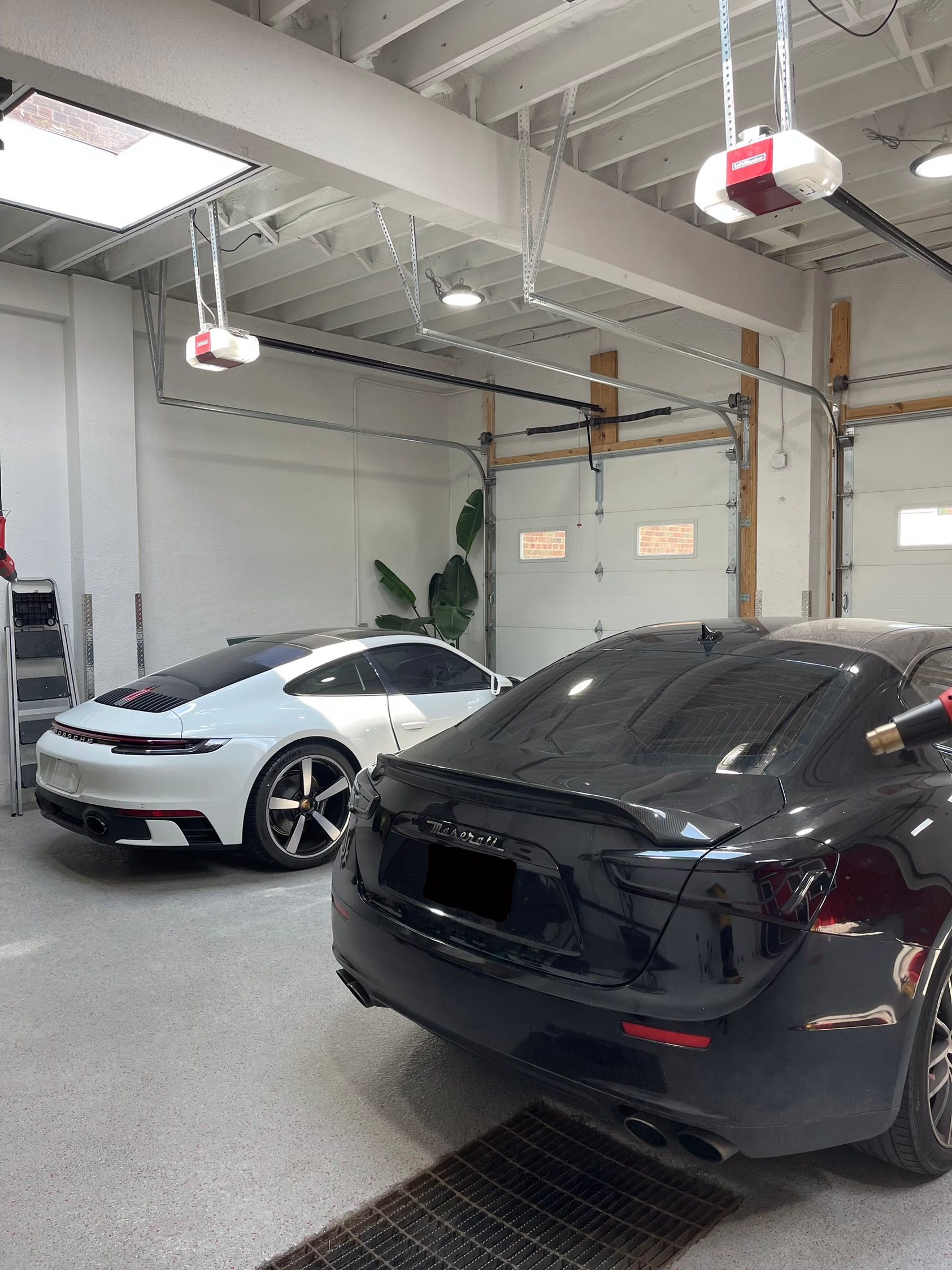 Black and silver RV parked in a garage. The vehicle has large tires and a side door with steps.