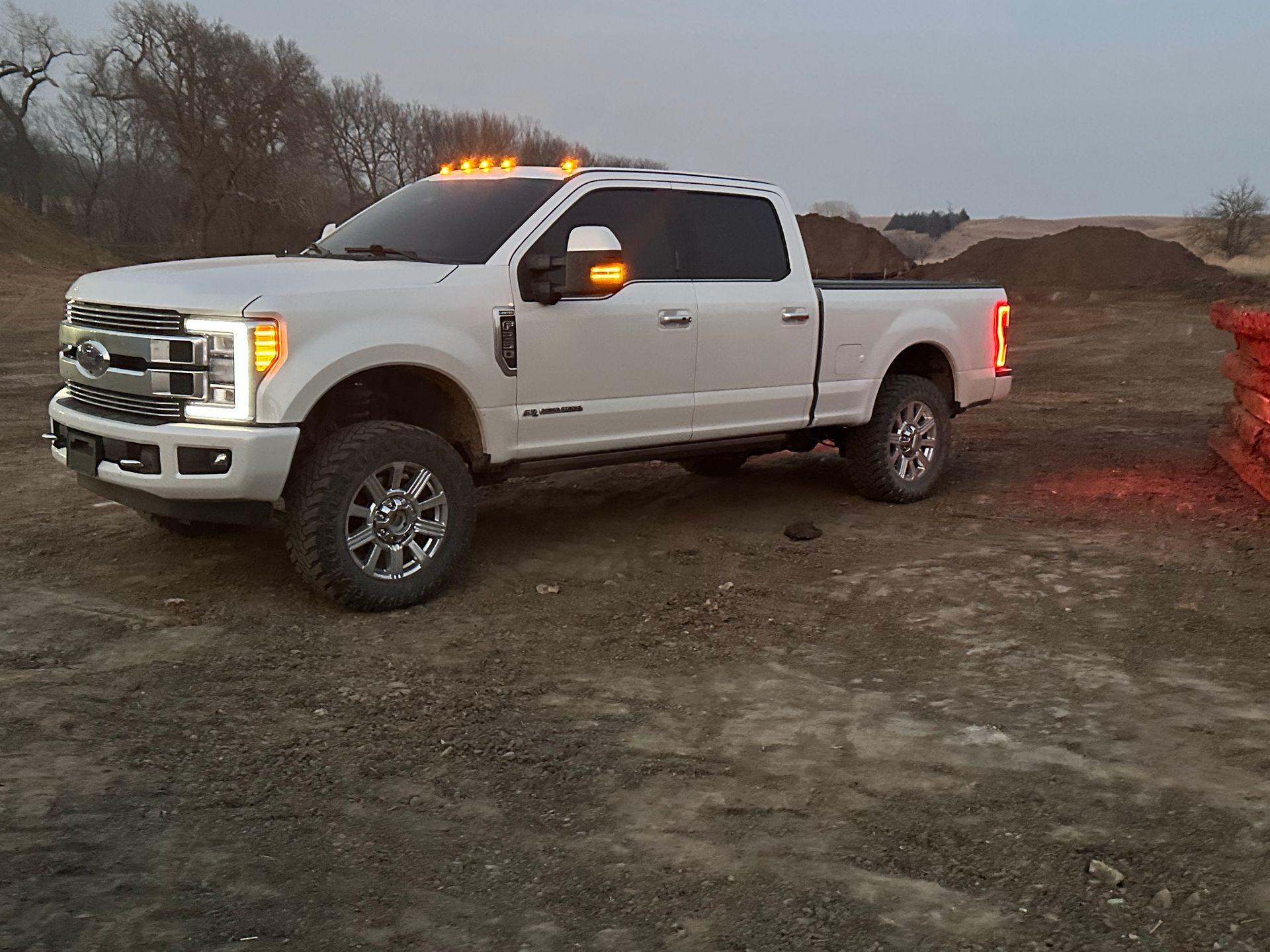 White Ford pickup truck on gravel in a rural setting, daytime.