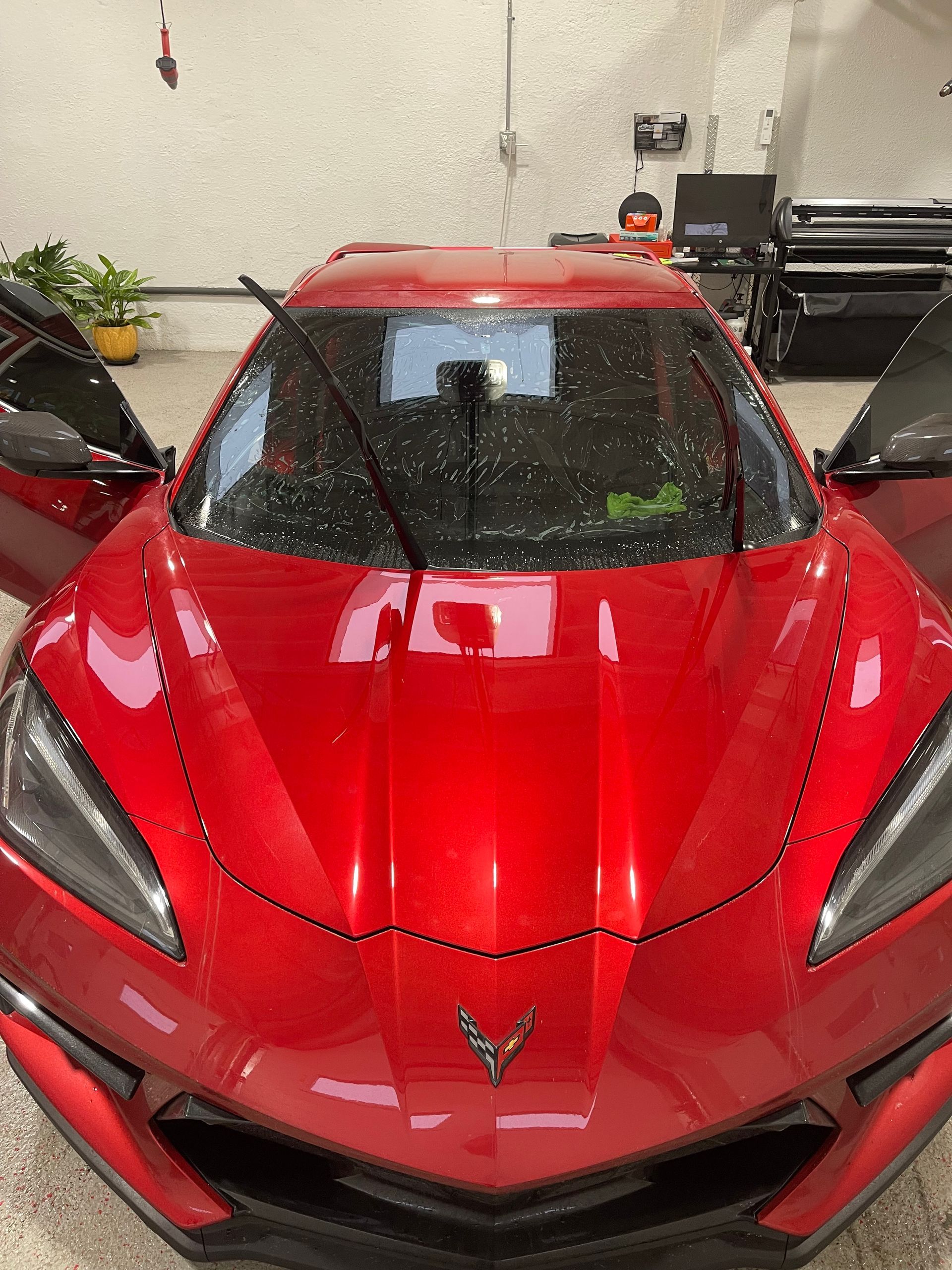 Person in blue applying film to a car's glossy surface.