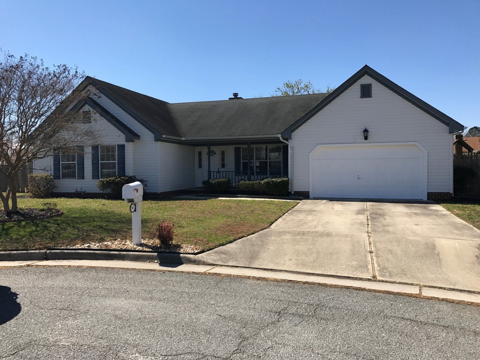 A white house with a driveway and a mailbox in front of it