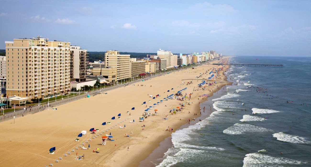 An aerial view of a beach with lots of people and buildings in the background.