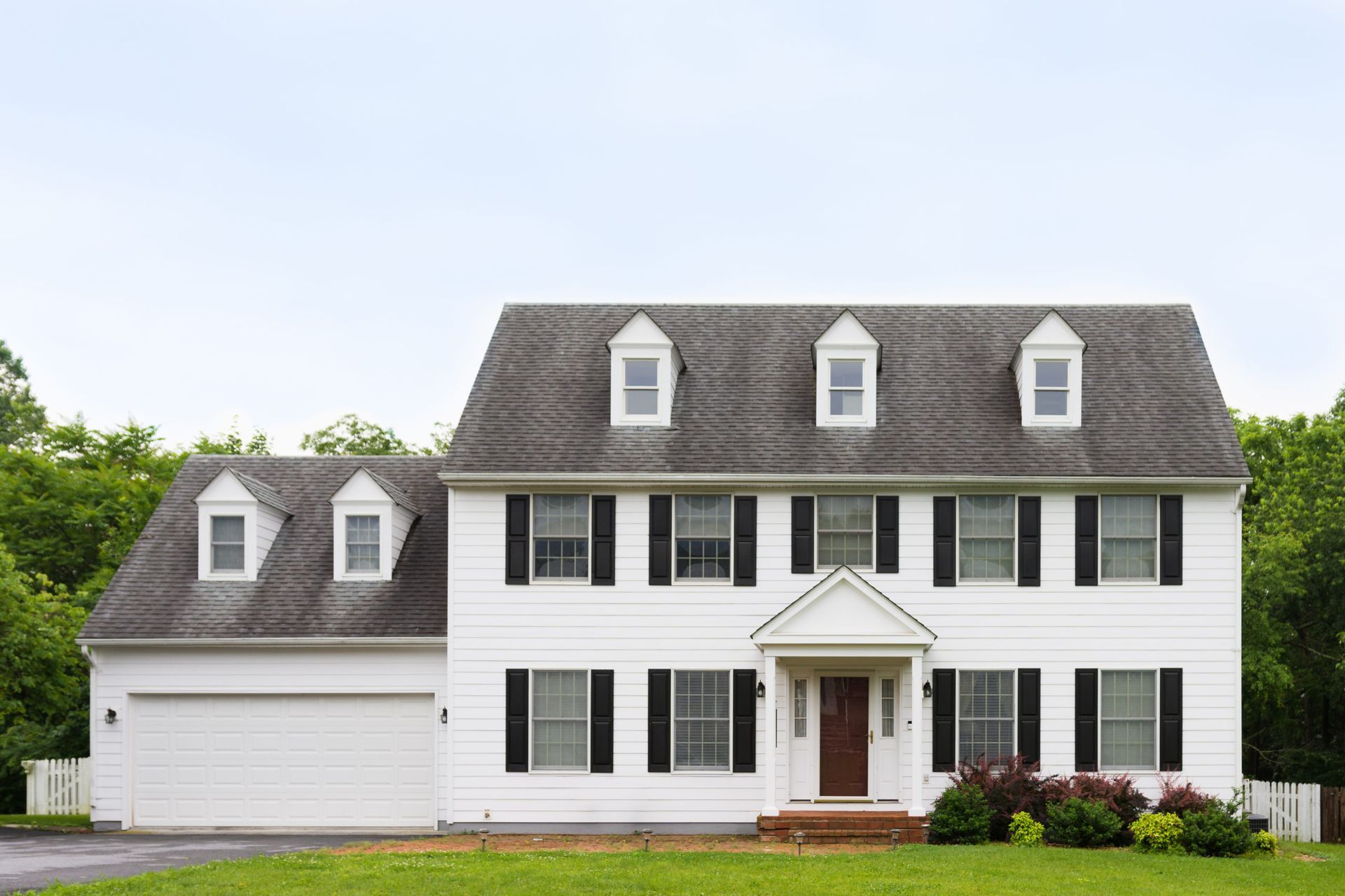 A large white house with black shutters and a gray roof