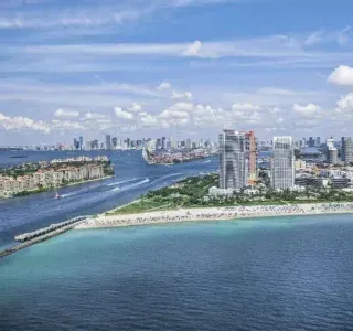 Aerial view of Miami Beach, Florida, with ocean, coastline, and city skyline under a blue sky.