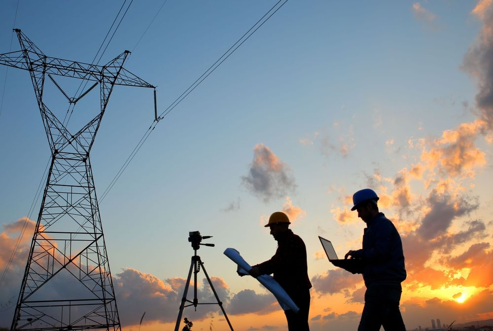 Two contractors standing by an electrical tower