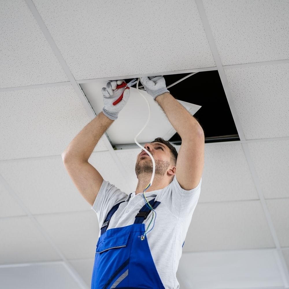 A man in blue overalls is installing an LED fixture