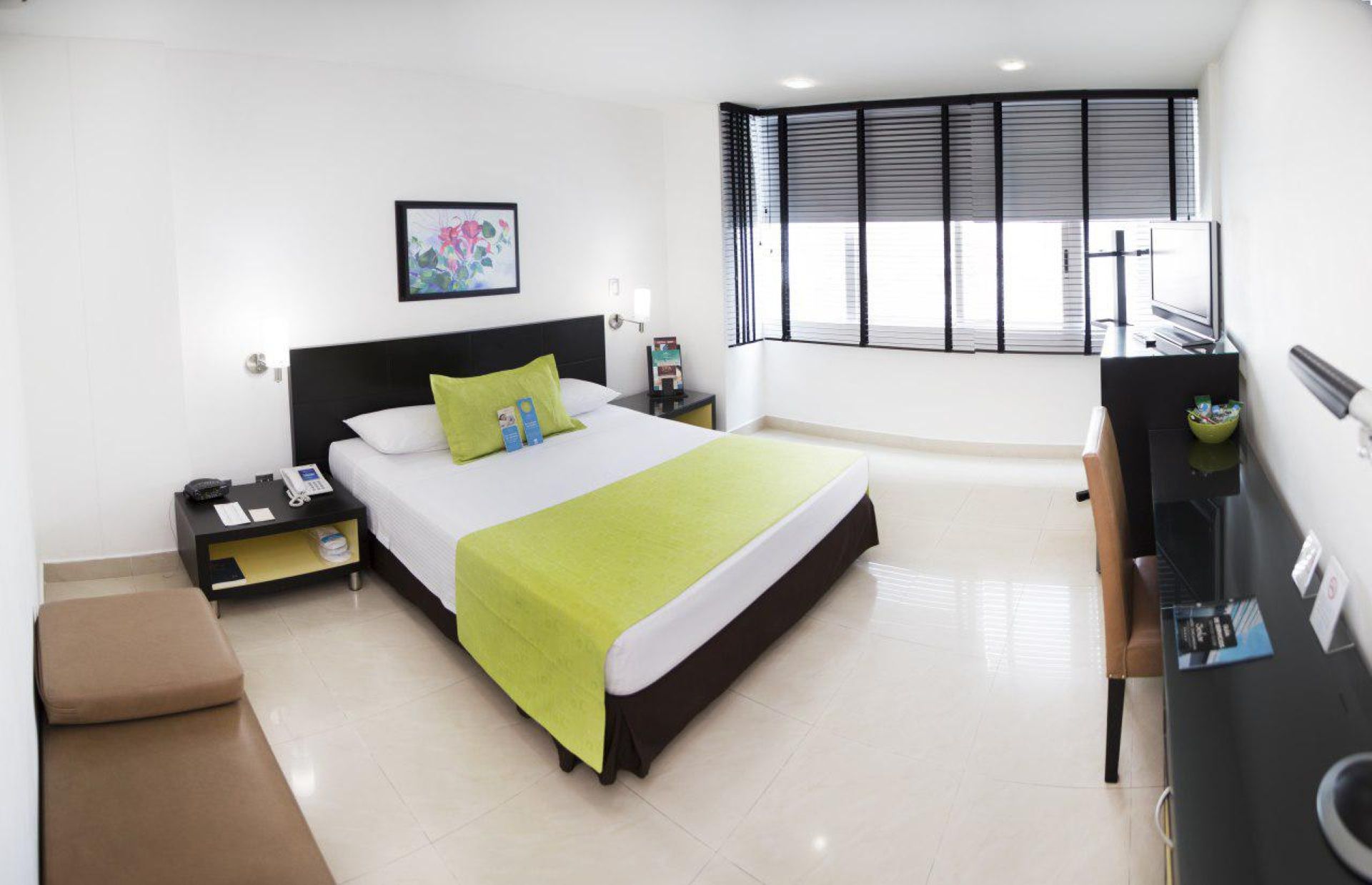 Una habitación de hotel con una cama grande y muchas ventanas.