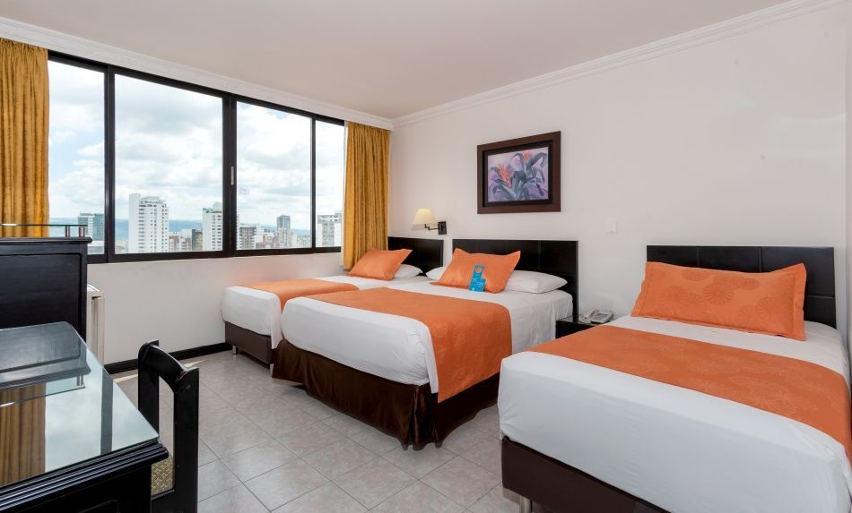 Una habitación de hotel con tres camas y una gran ventana.