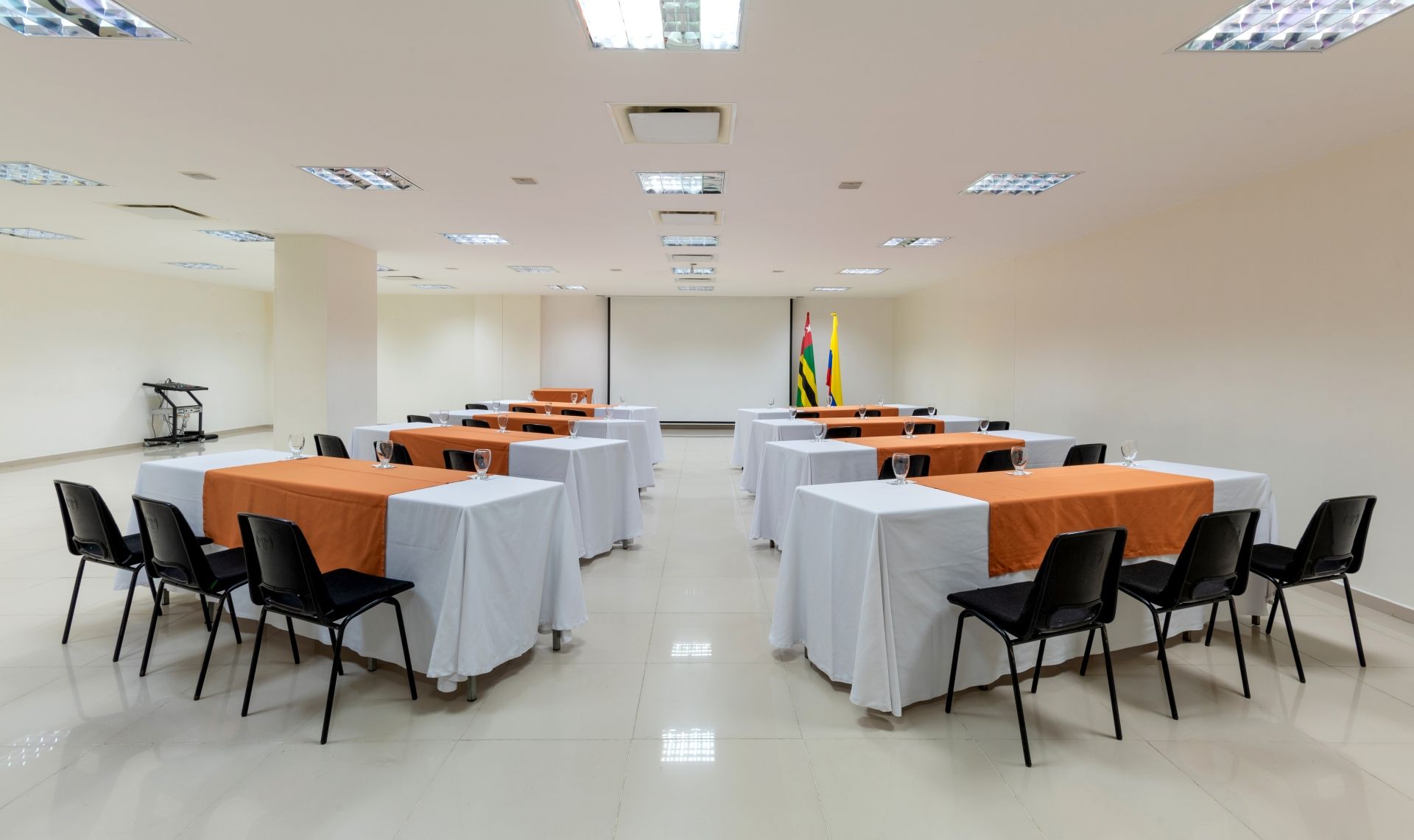 Una gran sala de conferencias con mesas y sillas preparadas para una reunión.