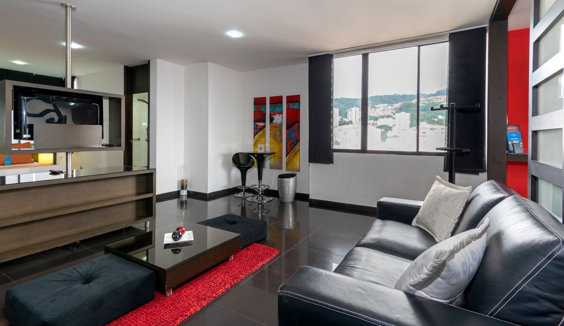 Una sala de estar con un sofá negro y un televisor de pantalla plana.