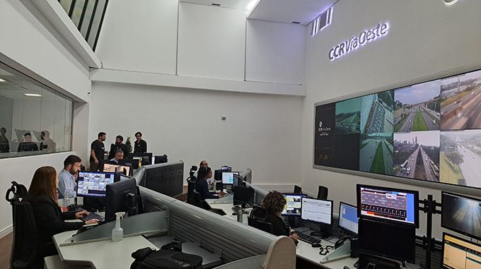 A group of people are sitting at desks in a control room.
