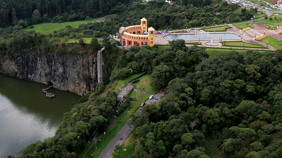 An aerial view of a lake surrounded by trees and a building.