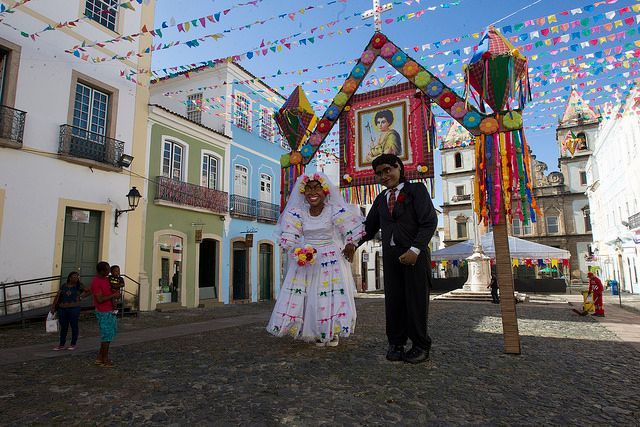 A bride and groom are posing for a picture in front of a colorful archway.
