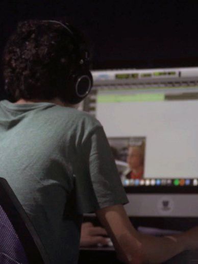 A man wearing headphones is looking at a computer screen