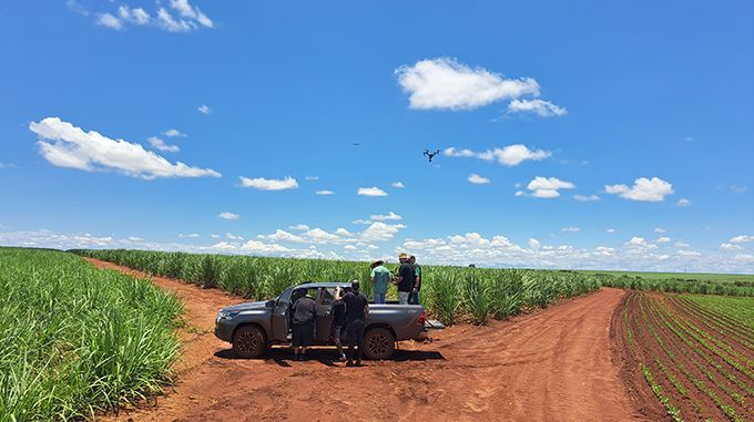 A group of people are standing in the back of a truck in a field.