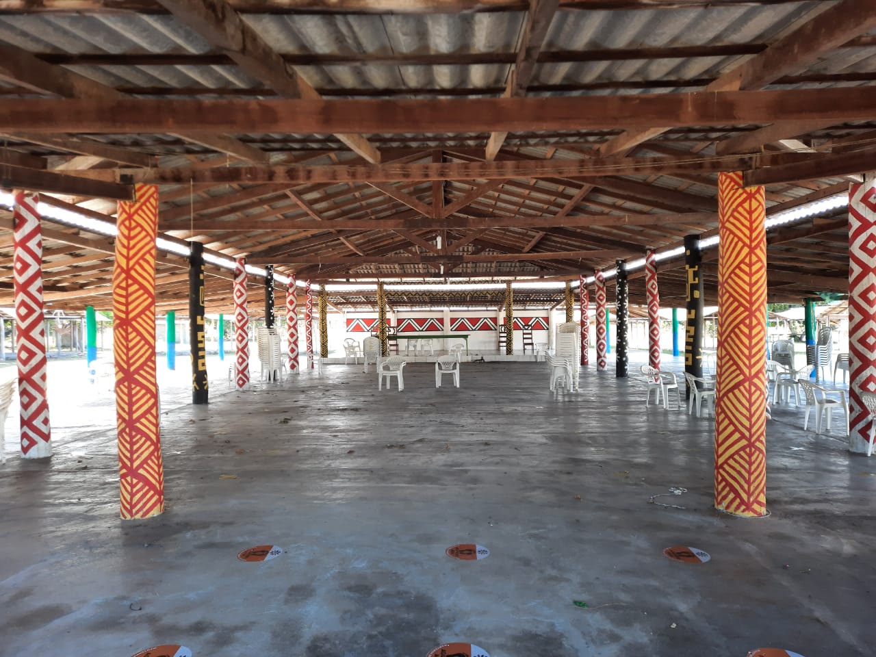 A large room with tables and chairs under a roof