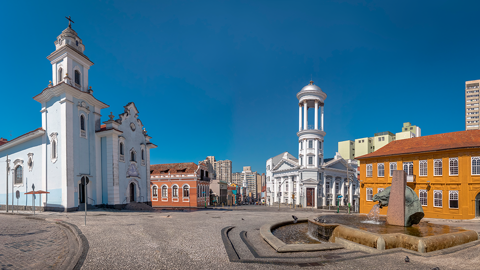 A church and a fountain in a city square with a blue sky in the background.